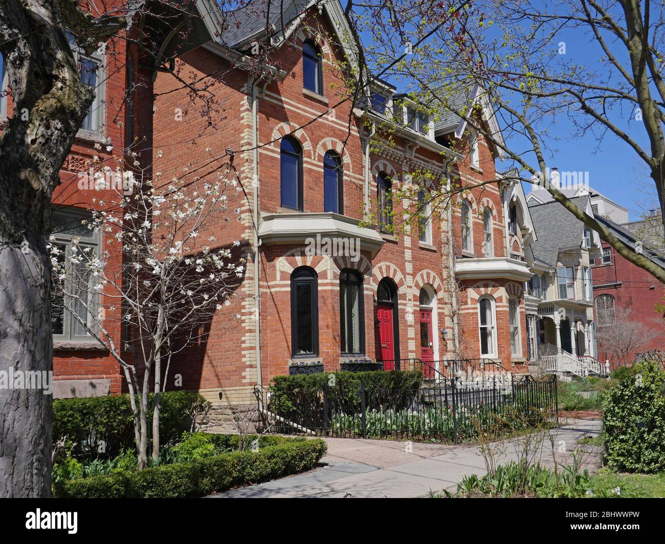 Street of renovated Victorian houses with pointy gables and front gardens Stock Photo