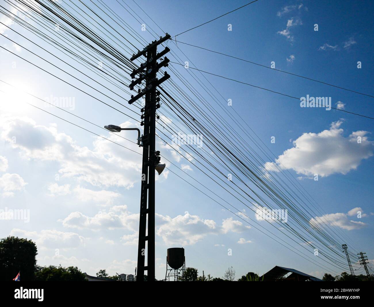 Silhouette Electric pole connect to the high voltage electric wires on sunlight blue sky