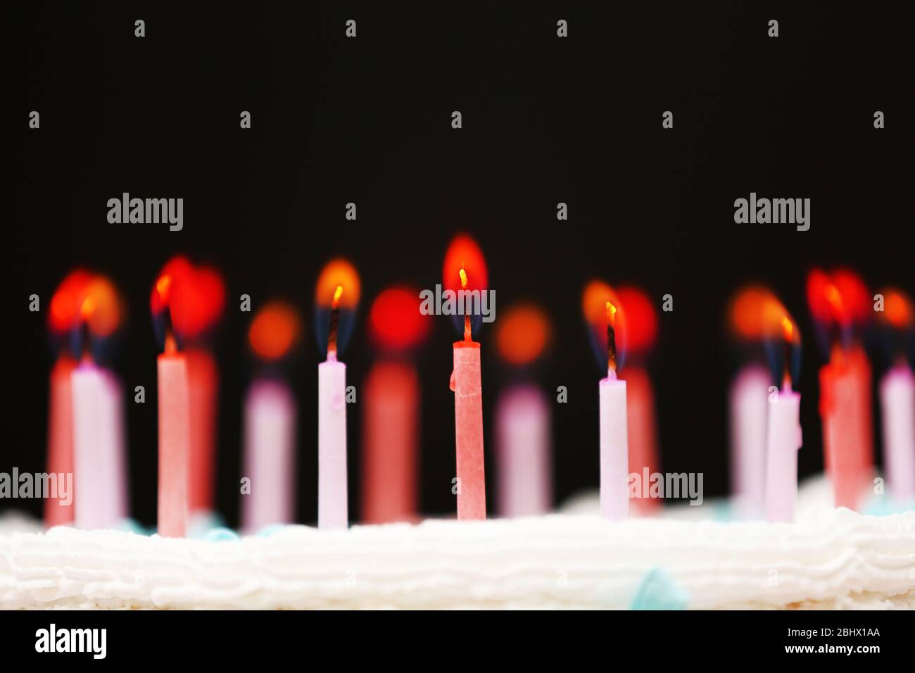 Candles on birthday cake on black background Stock Photo - Alamy