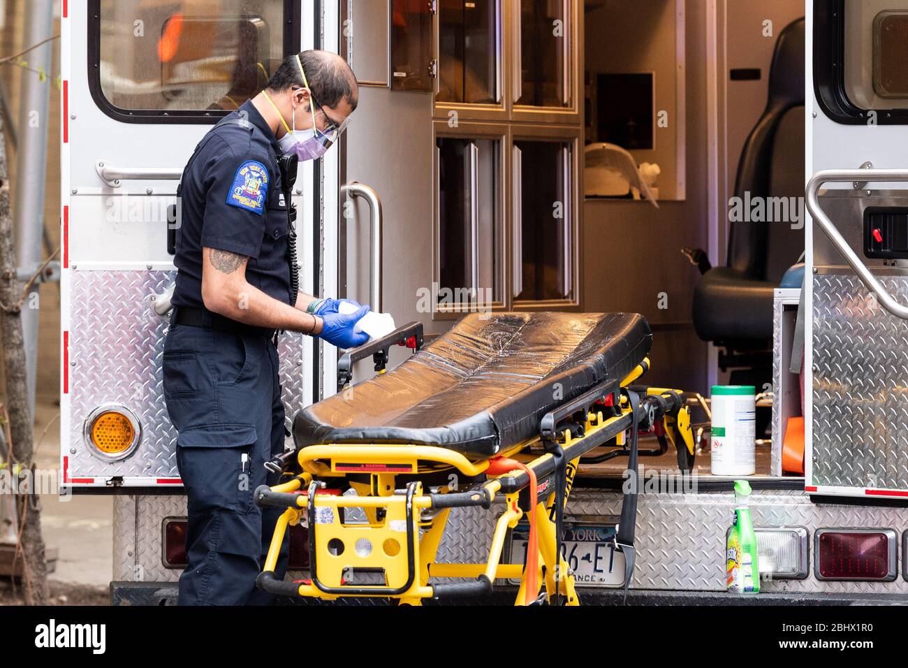 New York, United States. 27th Apr, 2020. Ambulance staff clean and disinfect a gurney after transporting patients to a hospital. Credit: SOPA Images Limited/Alamy Live News Stock Photo