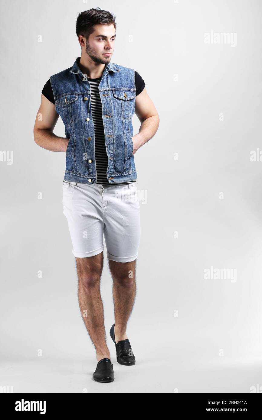 Man in white shorts and jeans vest on gray background Stock Photo - Alamy
