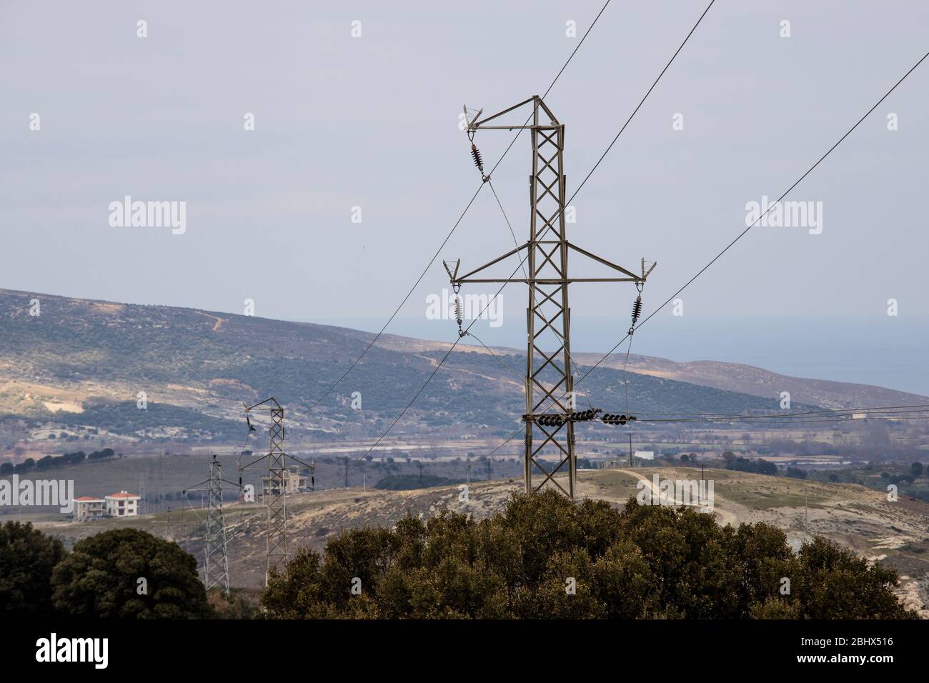 Power lines and transformers. There is a tree on the left and the weather is cloudy. Photographed in the winter. Stock Photo