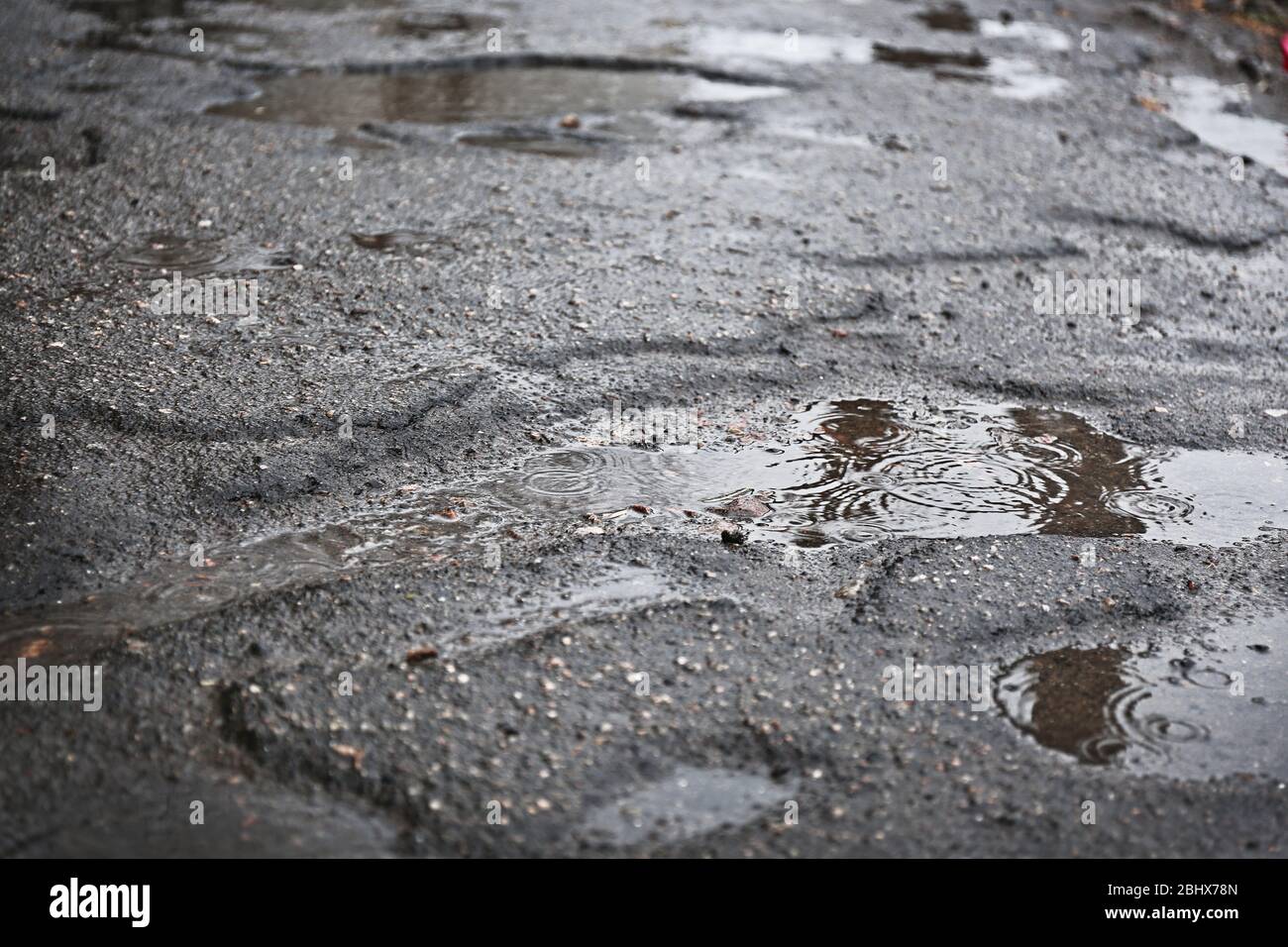 Holes with puddles on damaged asphalt background Stock Photo - Alamy