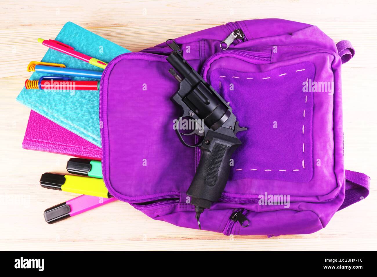 Gun in school backpack on wooden background Stock Photo - Alamy
