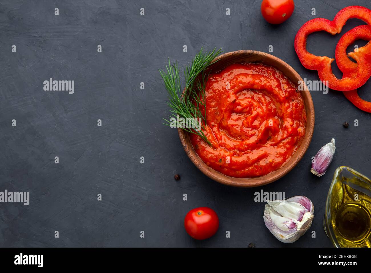 Flatley with pepper appetizer aivar and ingredients on a dark background. Top view, place for text. Stock Photo
