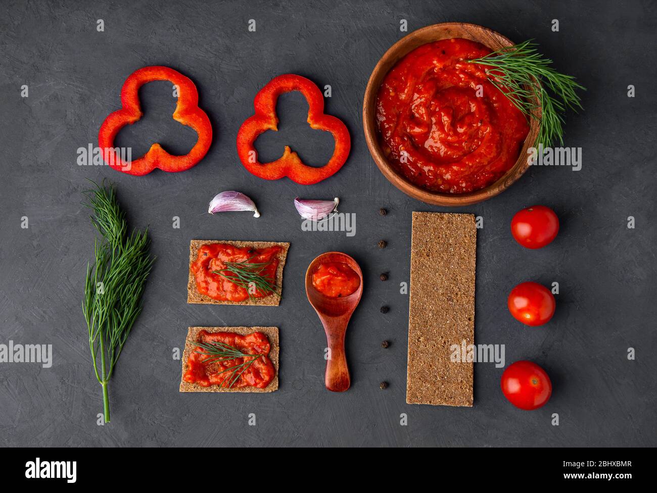 Flatlet with pepper appetizer ajvar and ingredients on a dark background. Knolling. Top view, place for text. Stock Photo