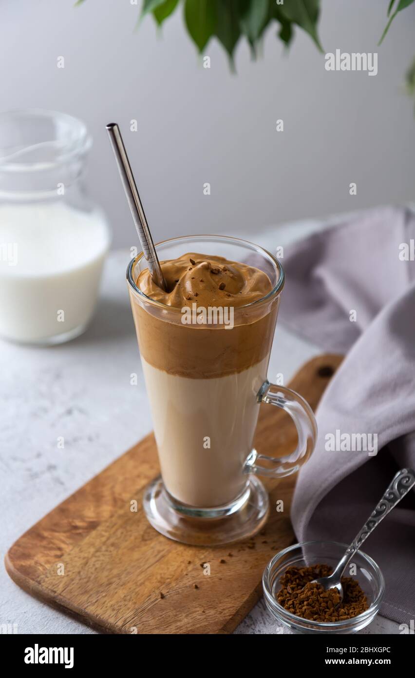 Cold dalgon coffee, a Korean drink with whipped coffee and milk in a glass glass on a light background Stock Photo