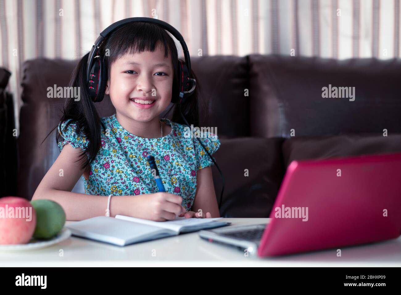 Cute asian little child girl studying  online lesson at home, social distance during quarantine, online education concept Stock Photo