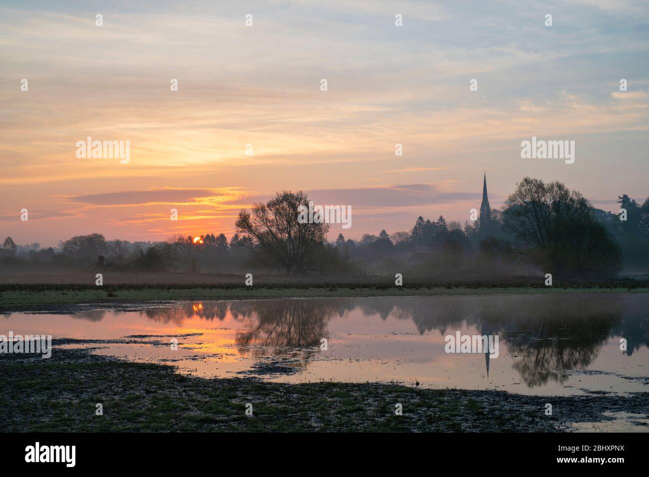 Mist, floods and Kings Sutton church spire at sunrise across the cherwell valley in spring. Kings Sutton, Nr Banbury, Northamptonshire, England Stock Photo