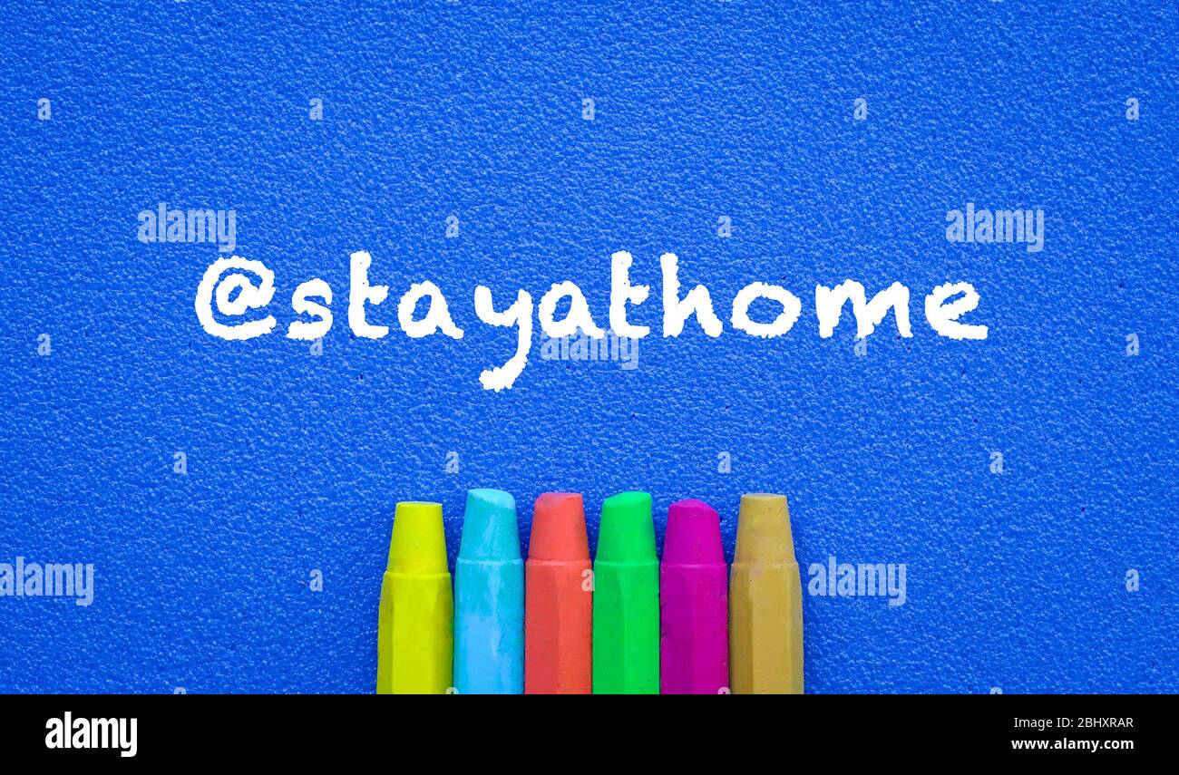 Stay at home. Words or typed text on blue board. Colorful crayons. Top view. Education concept.. Stock Photo