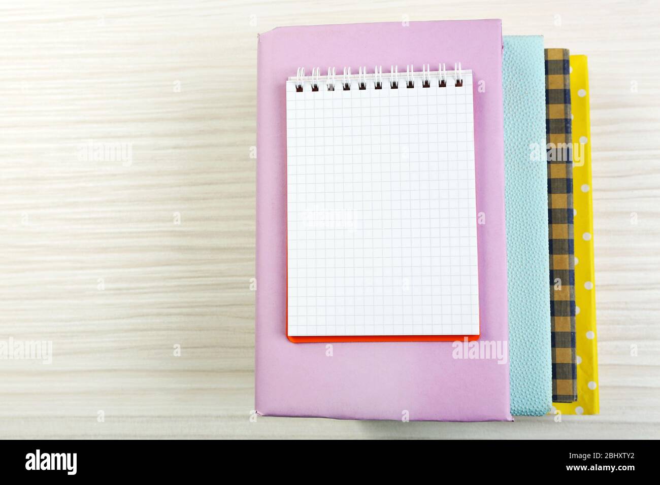 Notebook on top of pile of books and magazines on wooden background ...