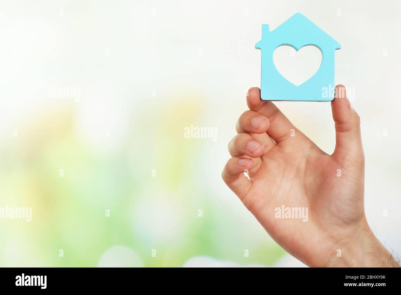 Female hand holding house on light blurred background Stock Photo - Alamy