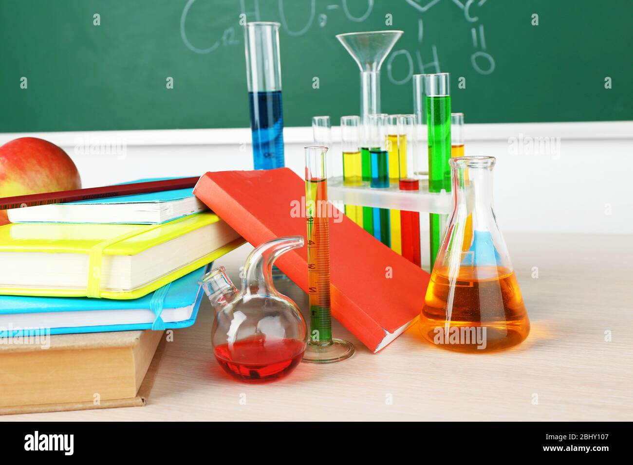 Desk in chemistry class with test tubes on green blackboard background