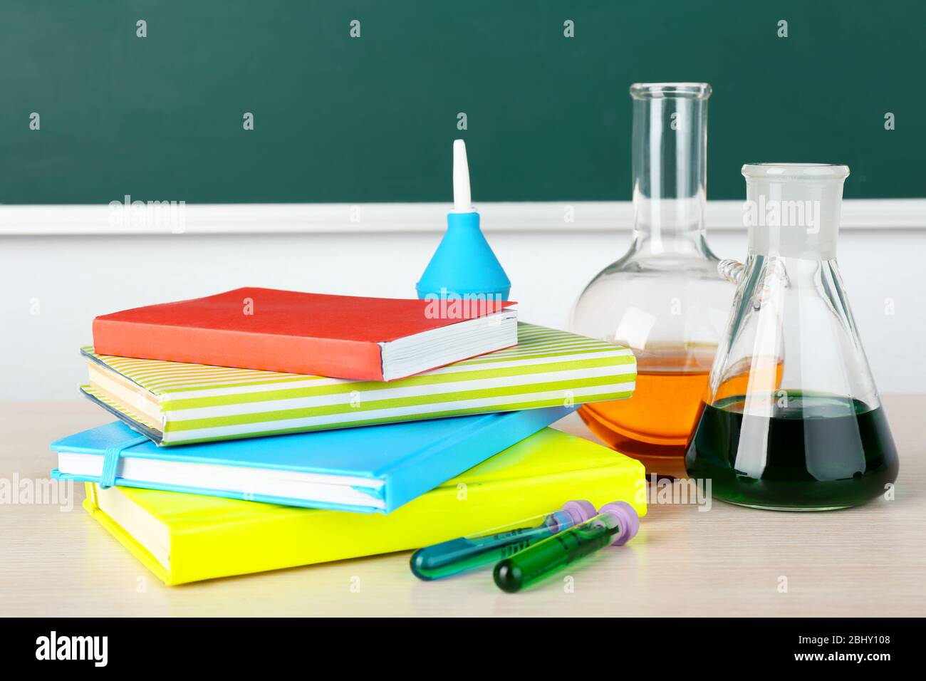 Desk in chemistry class with test tubes on green blackboard background Stock Photo
