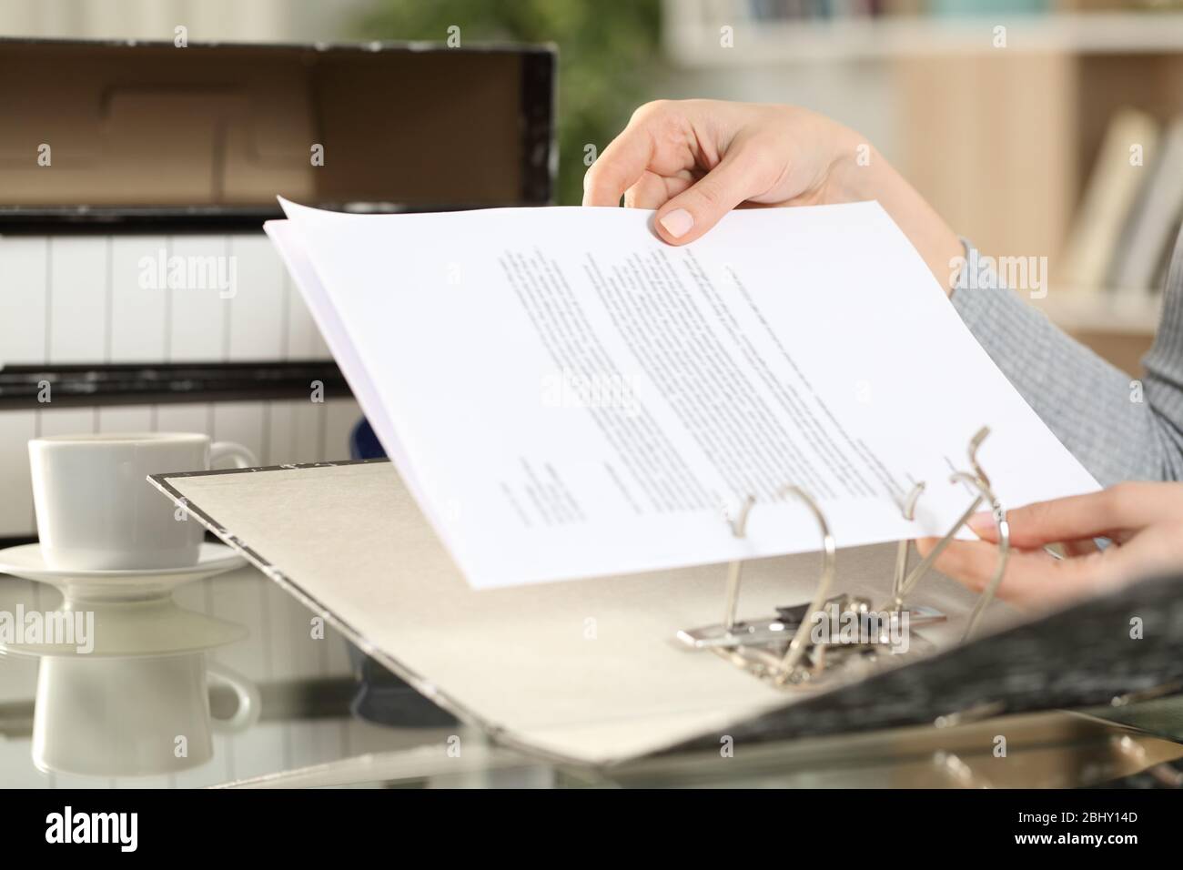Close up of girl hands putting documents on a ring binder at home Stock Photo