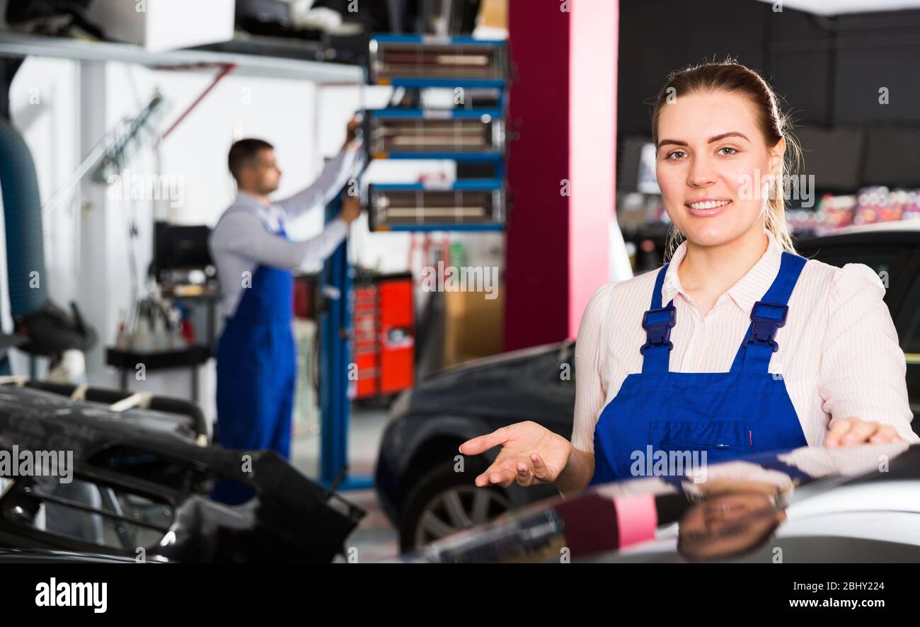 Friendly female mechanic showing car after painting in auto workshop Stock Photo