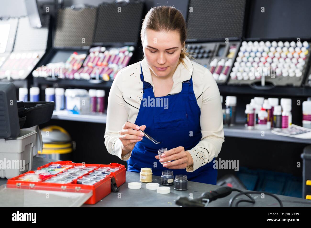 Focused female worker picking up color of fibers for car upholstery in auto repair shop Stock Photo