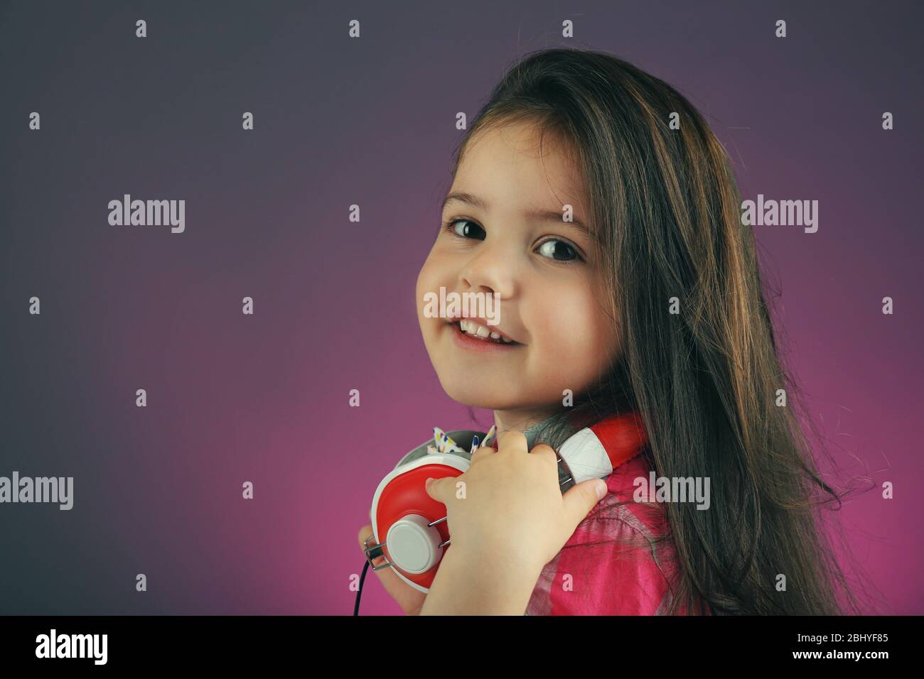 Beautiful little girl with headphones on colour background Stock Photo ...