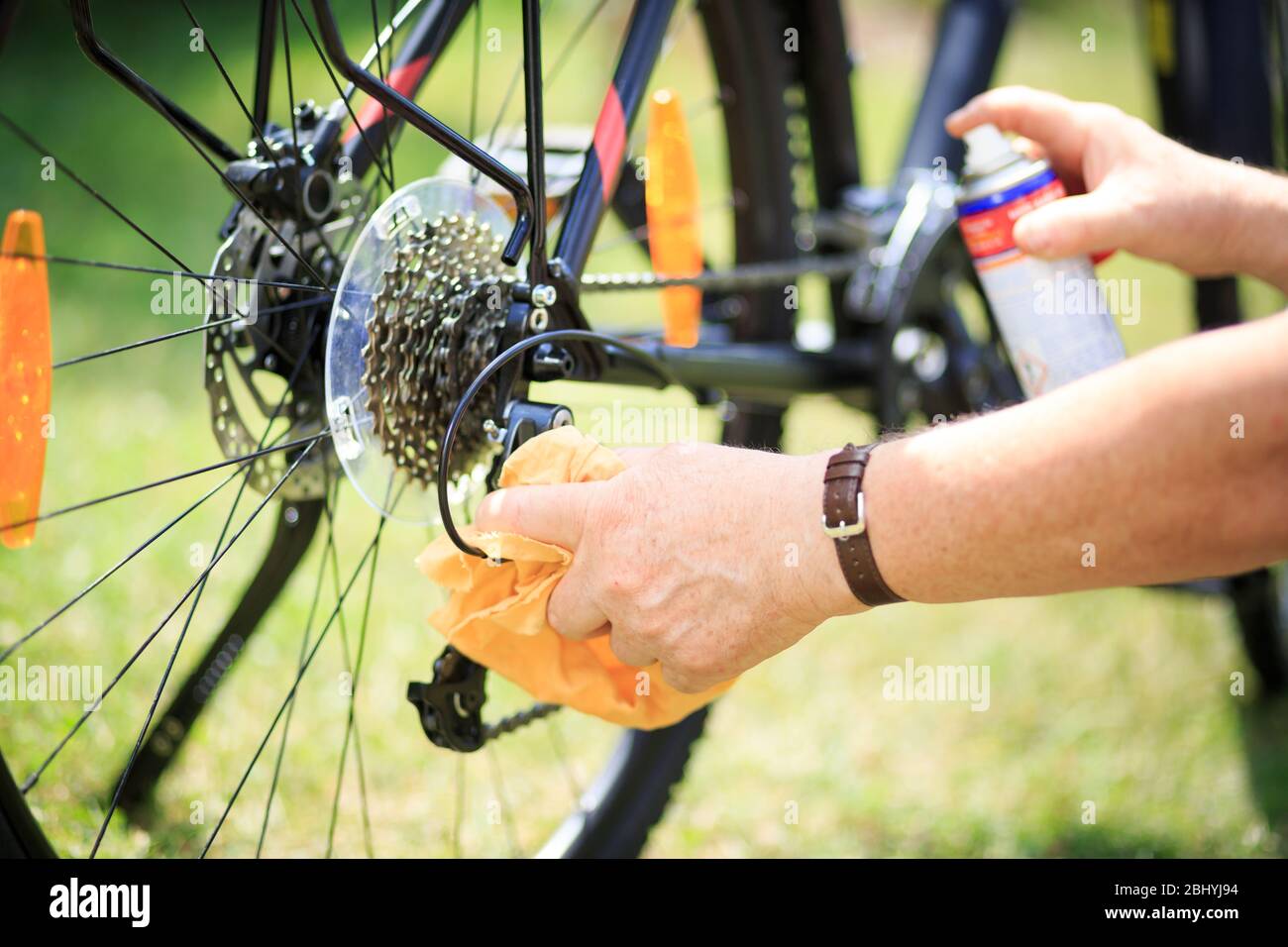 Senior man hands cleaning the bike by spray and rag, doing maintenance