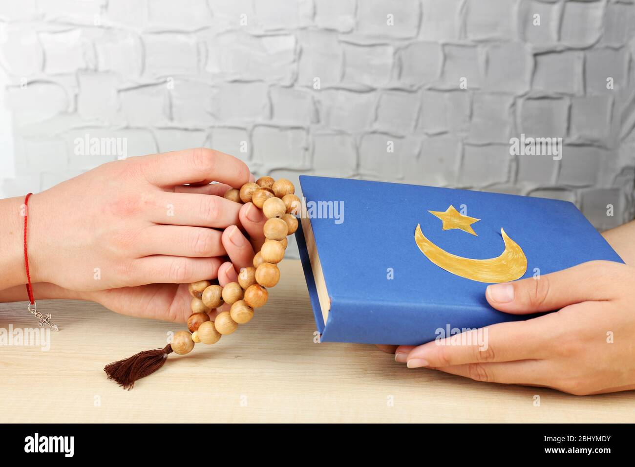 Hands of two friends with different religions symbols Stock Photo