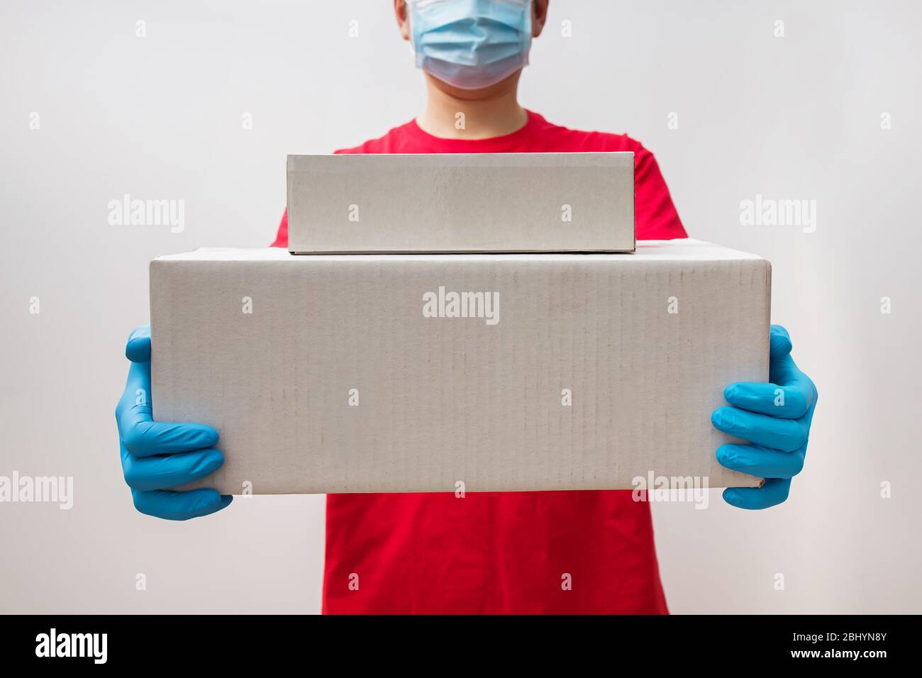 https://c8.alamy.com/comp/2BHYN8Y/delivery-man-holding-two-cardboard-boxes-in-protective-rubber-gloves-2BHYN8Y.jpg