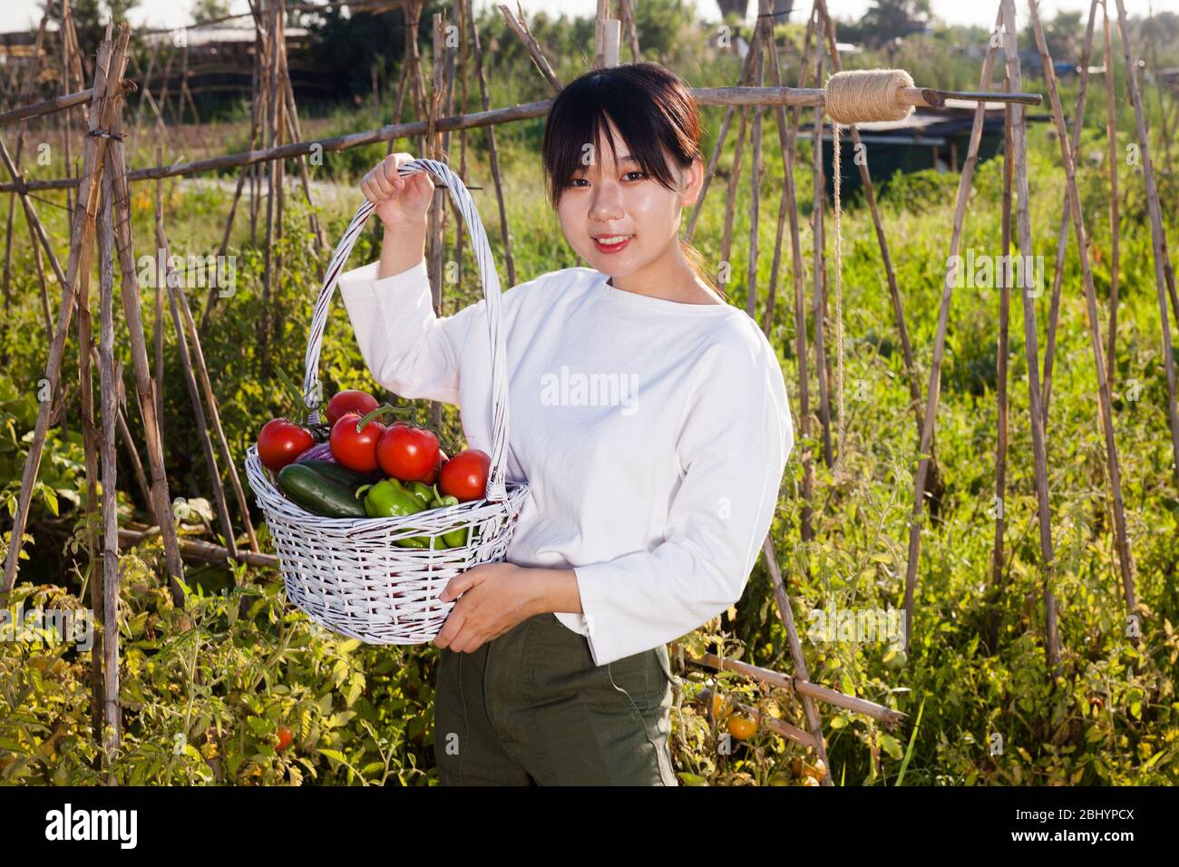 Portrait of young Asian woman holding basket full of harvested ...