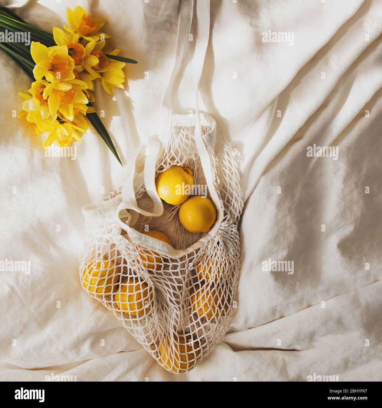 Spring flat lay with lemons and yellow flowers lying on the bed Stock
