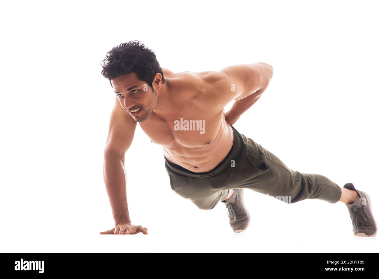 Man doing pushups with one hand in front of a white background. Stock Photo
