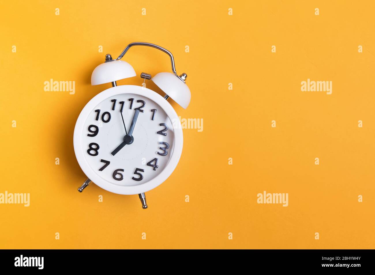White vintage alarm clock on yellow color background Stock Photo - Alamy