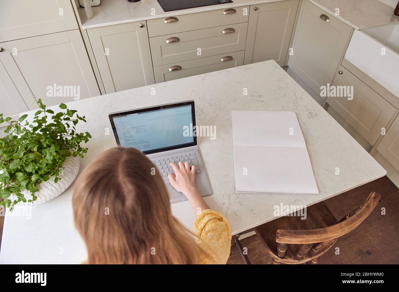 Young girl using laptop in kitchen. Stock Photo