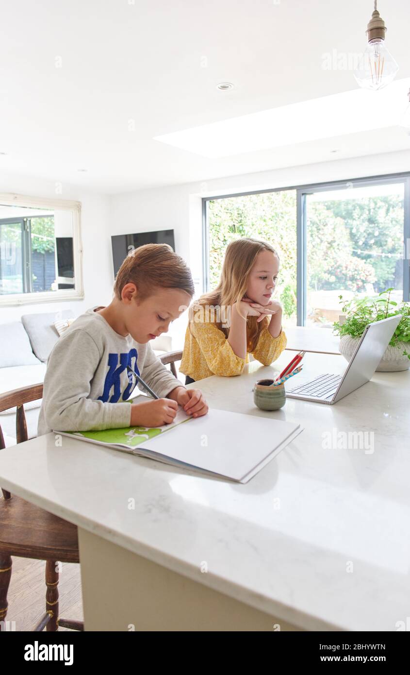 Young boy and girl studying at home on laptop and notepad. Stock Photo