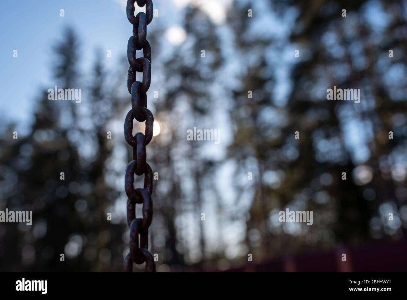 A rusty chain amid the sun and sky. Stock Photo