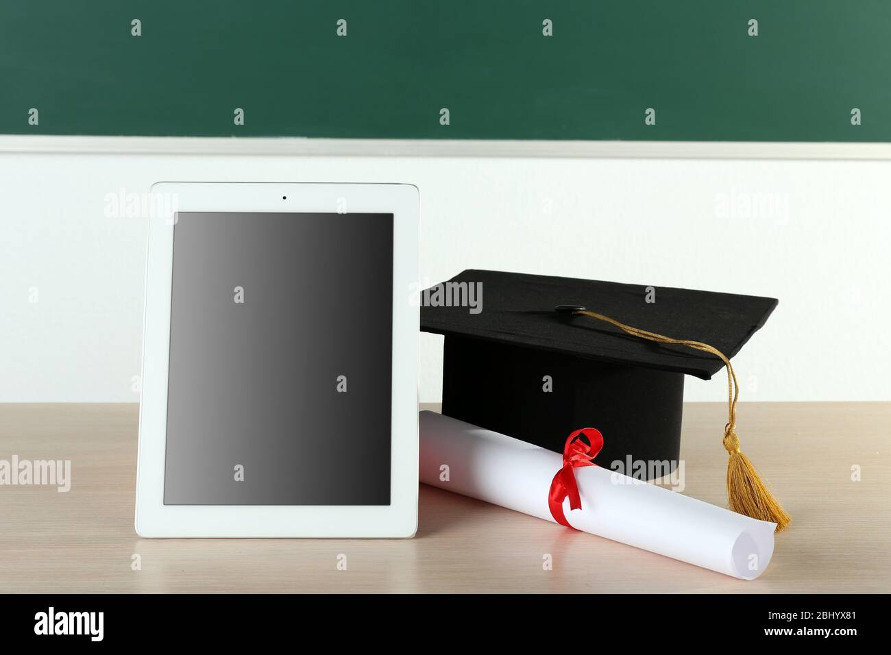 Graduation cap with tablet and diploma on table in class Stock Photo ...