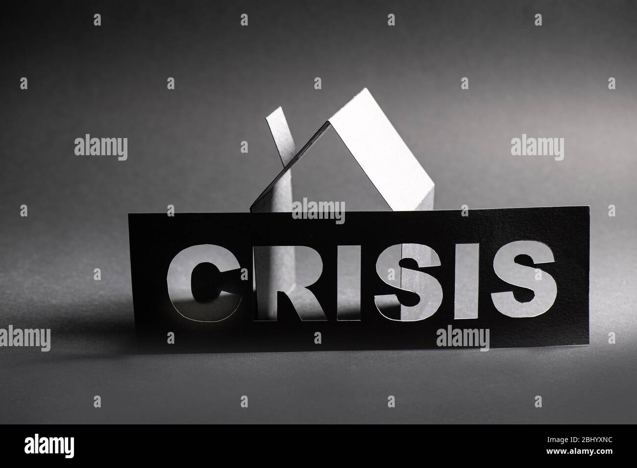 Crisis sign with cut out letters in front of cardboard house shape Stock Photo