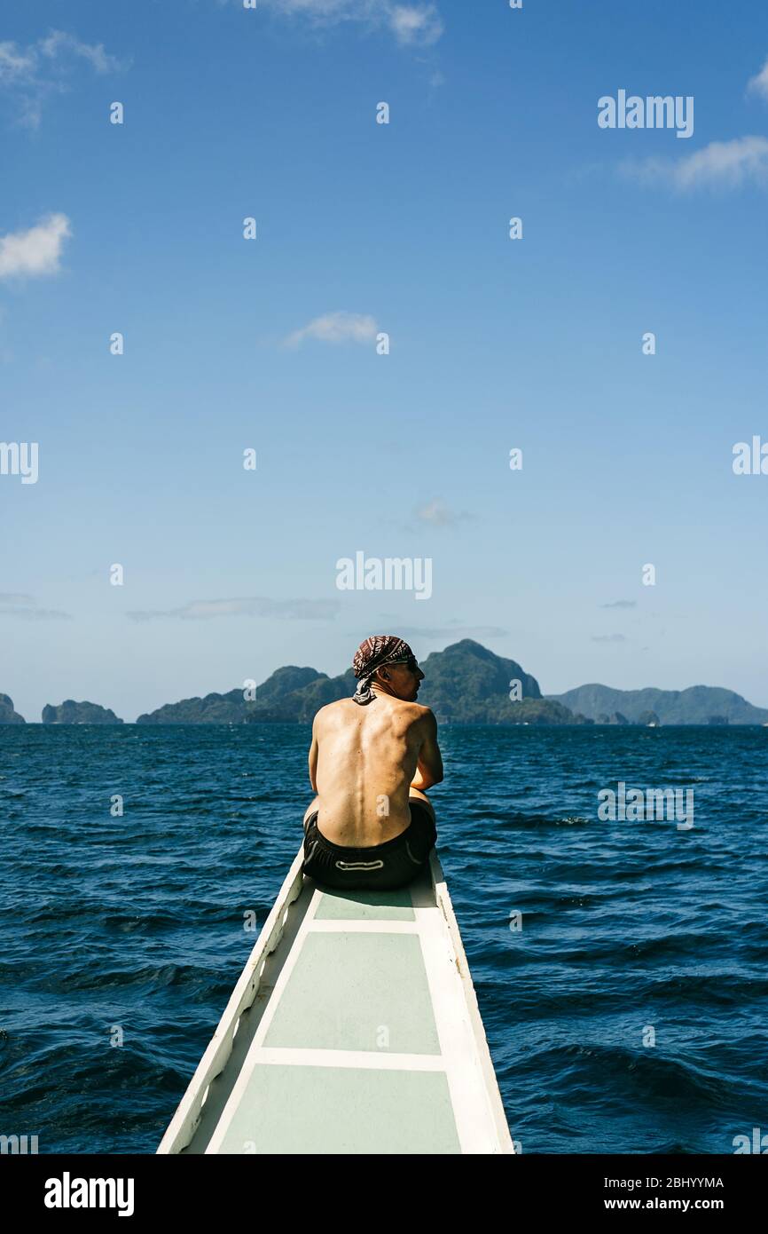 Man sitting on his back on the bow of a traditional Filipino boat on an