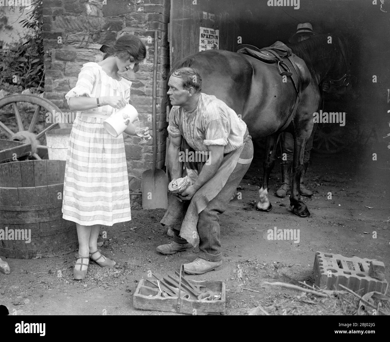 Miss Edna Maude , the seventeen year old dancer on holiday - giving the blacksmith a drink . - Stock Photo