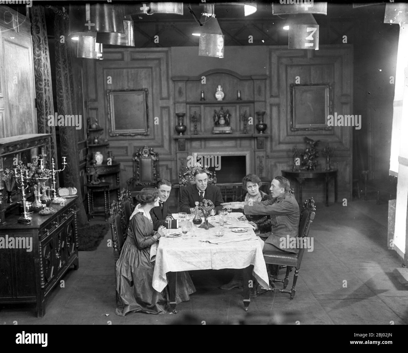 Filming a scene of ' Everybody ' s Business ' , a food economy film . Left to right ; Miss Renee Kelly , Mr Matheson Lang , Mr Norman KcKinnel , Miss Kate Rorke and Mr Gerald Du Maurier , as a soldier telling of his experiences - 1917 - Stock Photo