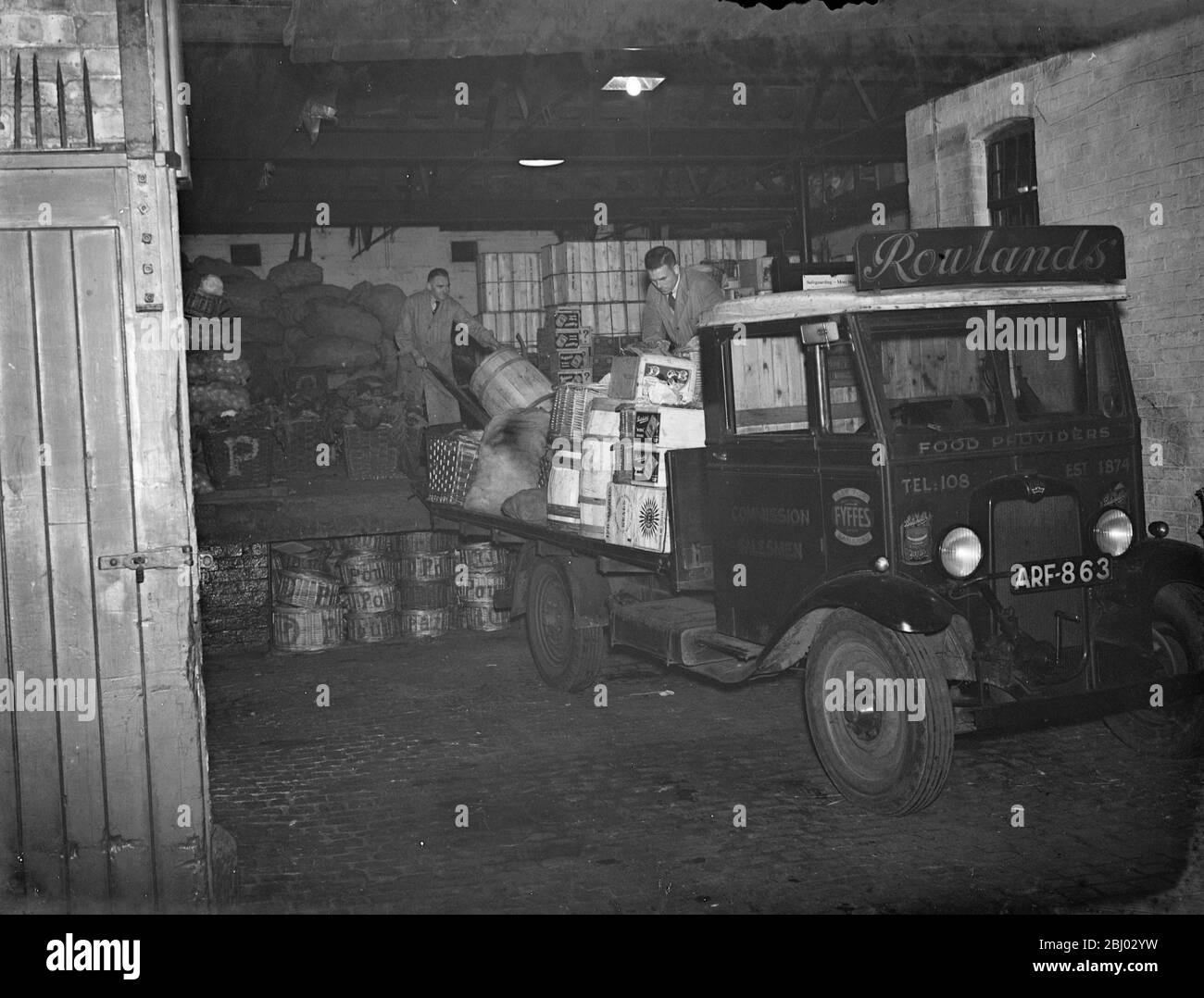 Green groceries are loaded onto a Rowlands truck for delivery to the shops . - 1937 . - Stock Photo