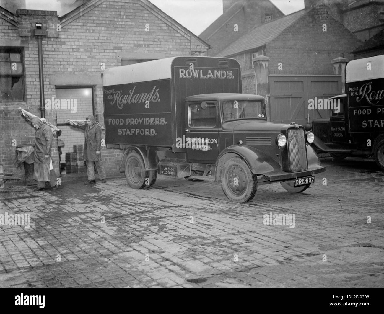 A Rowlands lorry unloading meat carcasses on the forecourt . 1937