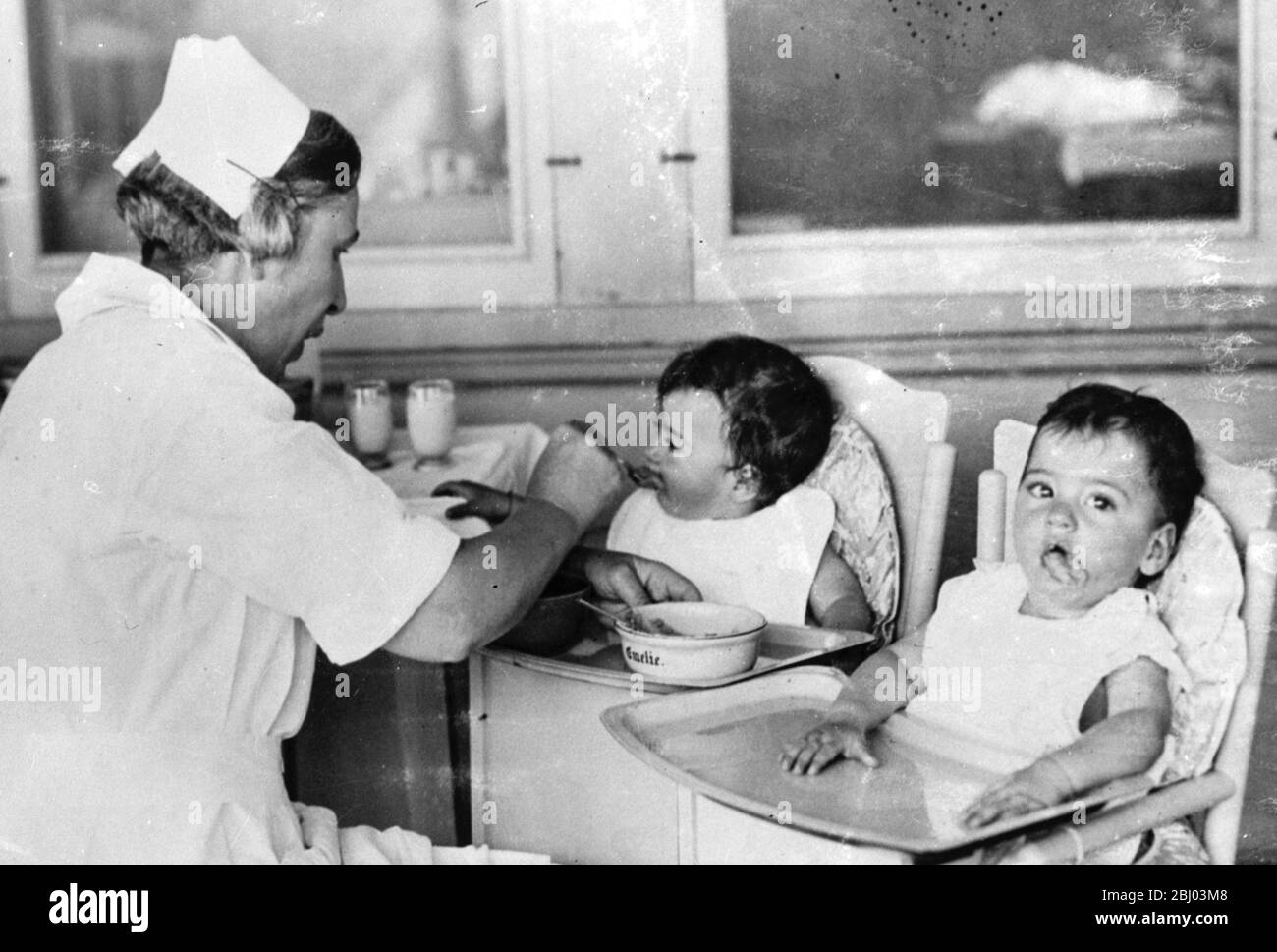 One of the Dione Quints feeding . Cecile takes a mouth of food from the nurse . - 1935 Stock Photo