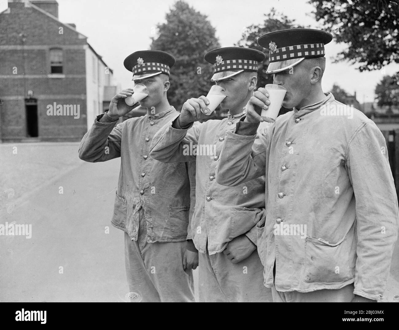 Three Scots Guards downing healthy glasses of milk from the new milk bar which has replaced the canteen and the beer bar at the Guards Depot , Caterham , where hundreds of recruits begin their army career. The barracks provide men with reading and writing rooms recreation rooms and restaurants. - 22 July 1937. Stock Photo