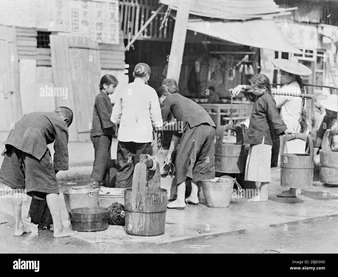 A thousand people are reported dead after a horrific dawn air raid on Canton, South China, by Japanese bombing planes. Many of the bombs fell in the densely populated poorer districts of the city. Women and children drawing water at the public well in a poor district of Shanghai. Fresh drinking water is scarce and many people are now leaving by walking water through the streets. - 23 September 1937 Stock Photo