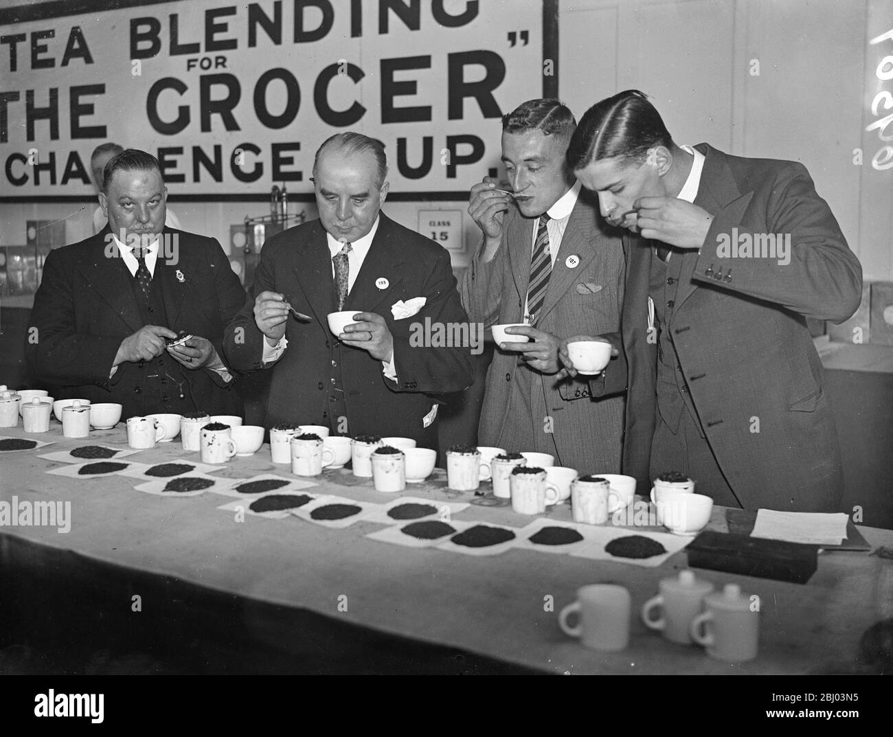 Tea tasters at grocers exhibition. - Grocers from all parts of the country are competing for the title of Champion Grocer at their 41st International Exhibition at the Royal Agricultural Hall, Islington, London. - Photo shows, judges tasting tea blends at the exhibition. - Left-to-right, Mr John Gregory, a judge, Mr Francis Shenton, last year's champion blender, Mr PC Gosling, Mr N Clark. - 20 September 1937 Stock Photo
