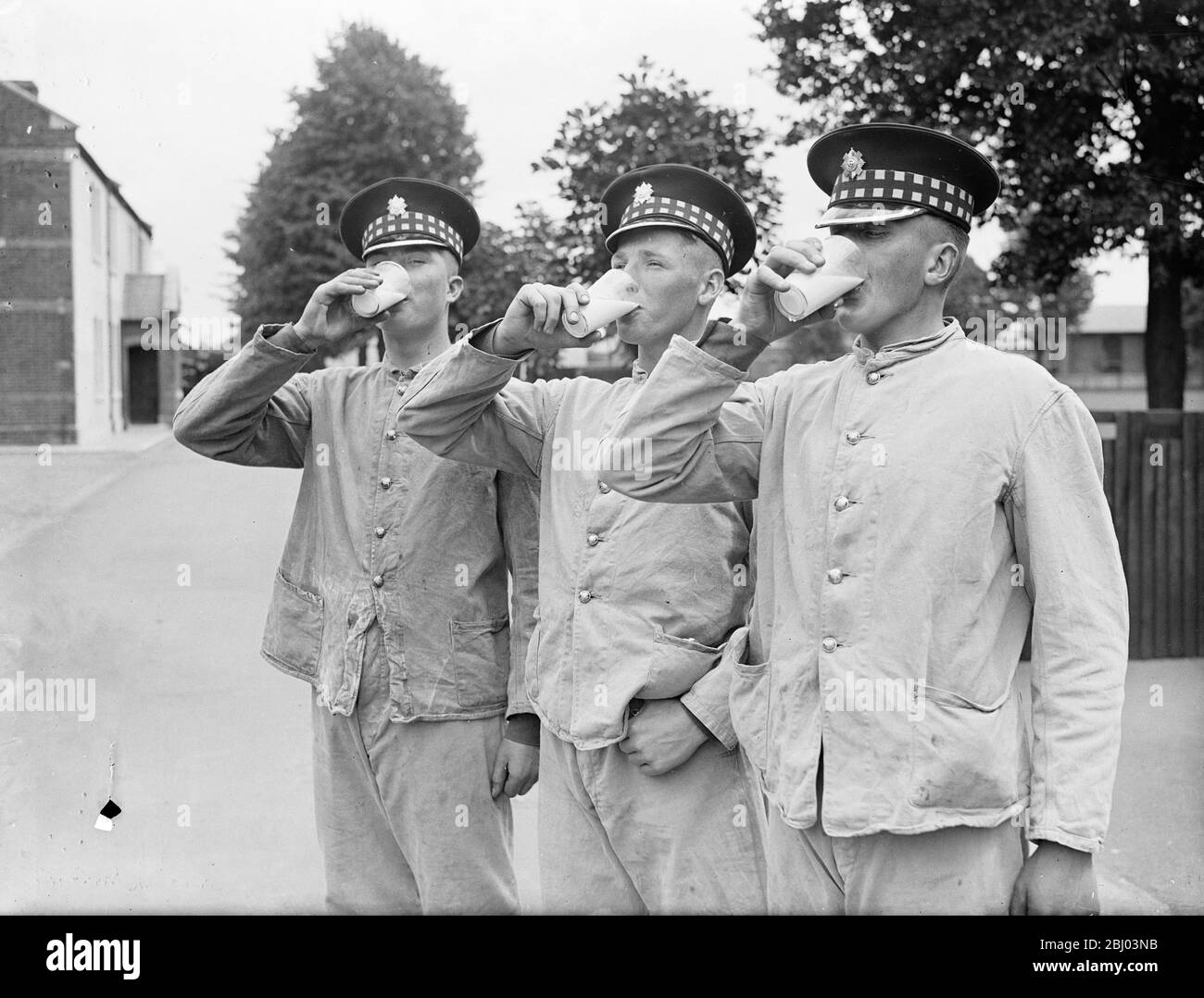 Three Scots Guards downing healthy glasses of milk from the new milk bar which has replaced the canteen and the beer bar at the Guards Depot , Caterham , where hundreds of recruits begin their army career. The barracks provide men with reading and writing rooms recreation rooms and restaurants. - 22 July 1937. Stock Photo