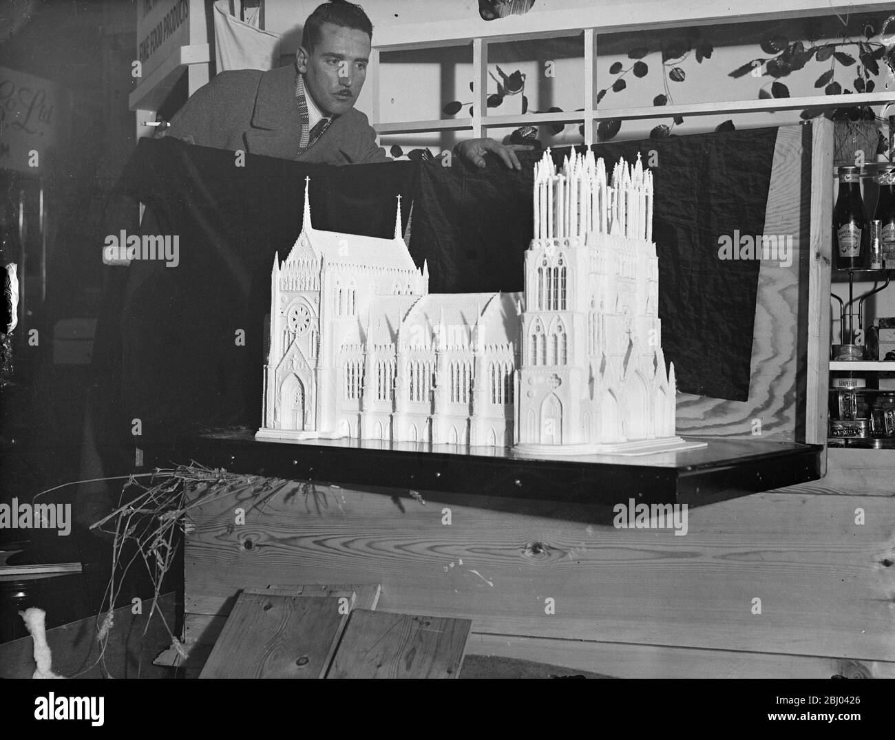 Rheims Cathedral in sugar. - Some wonderful models made entirely of sugar will be on show at the Hotel, Restaurant and Catering Exhibition, which opens in the National Hall at Olympia, London tomorrow, (Tuesday). Most of the models took many months to make. - Photo shows, Mr JJ Williams, head chef of the Royal Exeter Hotel, Bournemouth, with his sugar model of the restored Rheims Cathedral, which took him three months to make. - 29 November 1937 Stock Photo