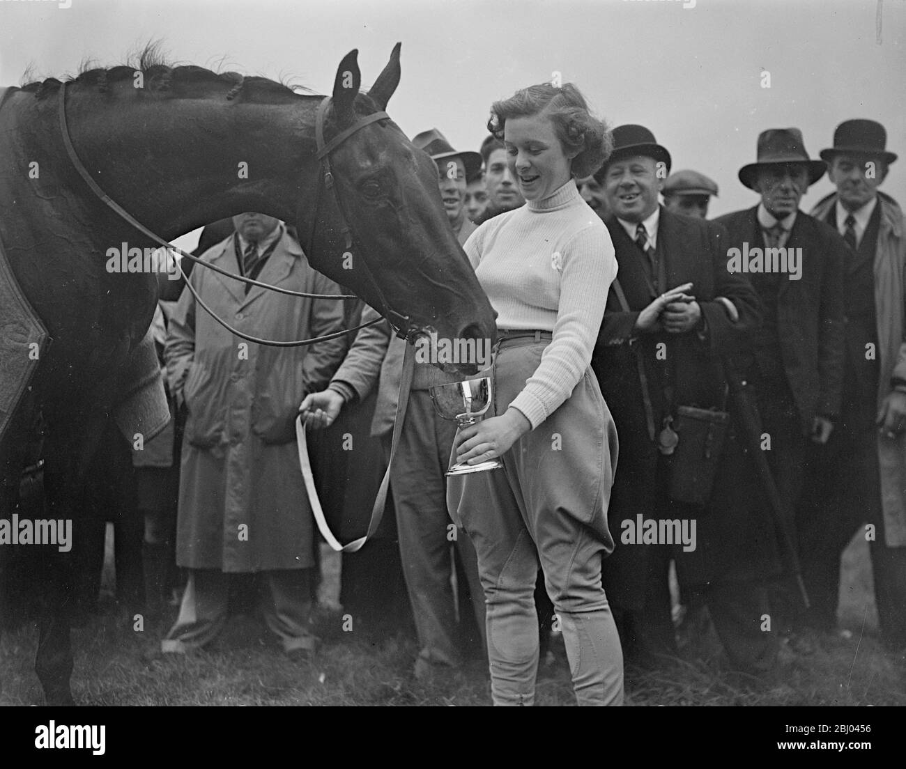 Jimmy petted!. - Trainers daughter wins historic race at Newmarket. - Riding Mr P Thrales 'Jimmy's pet' Miss A Thrale, daughter of the trainer, one the historic Newmarket Town Plate. The only event in which women riders take part, and Newmarket. - Photo shows, Miss A Thrale, the winner, giving her mount 'Jimmy's Pet', a drink from the cup. - 14 October 1937 Stock Photo