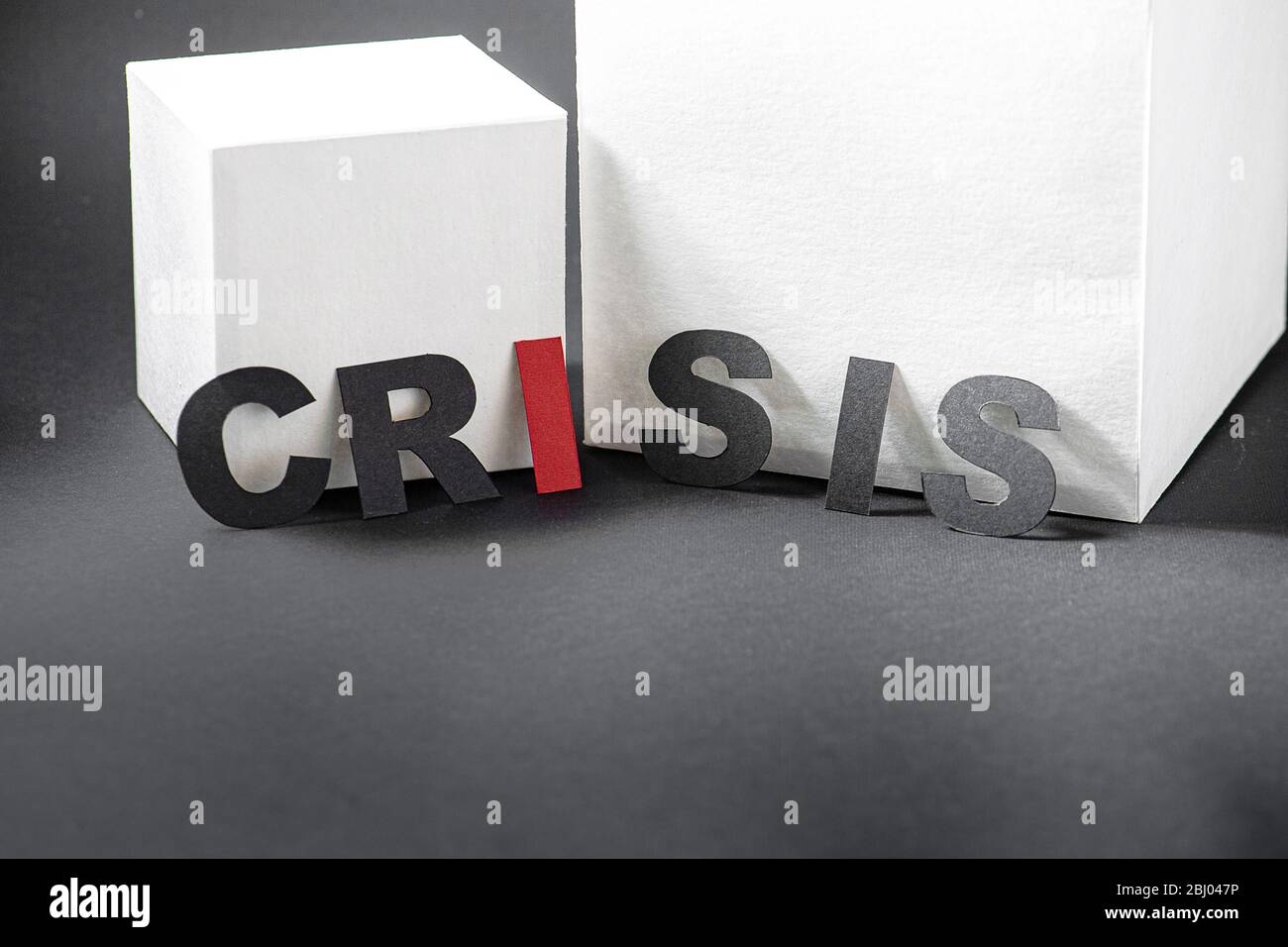 Crisis word letters in front of white cubes placed unevenly Stock Photo