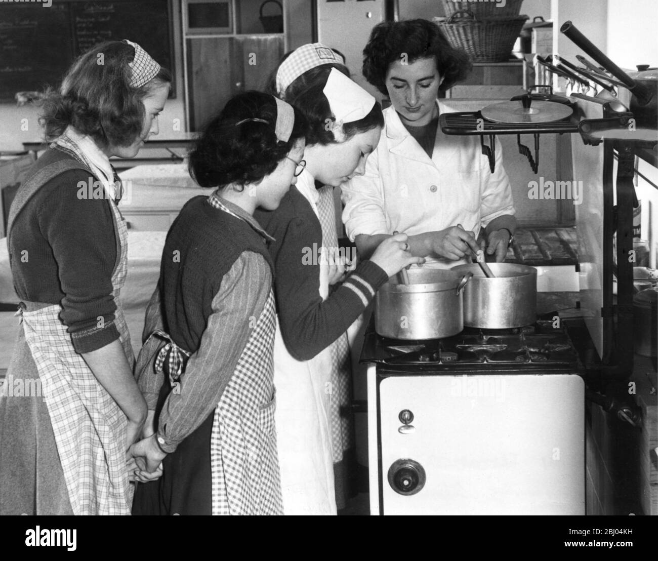 Barclay Secondary Modern School, Stevenage. Miss Cleaver shows the girls the correct way to cook during a Domestic Science lesson. 1949 Stock Photo