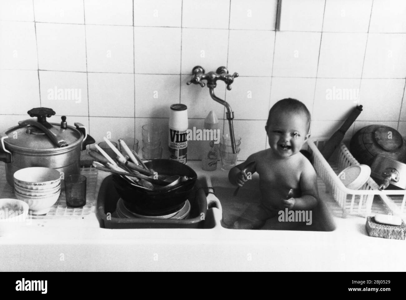 Baby in the kitchen sink! Stock Photo Alamy