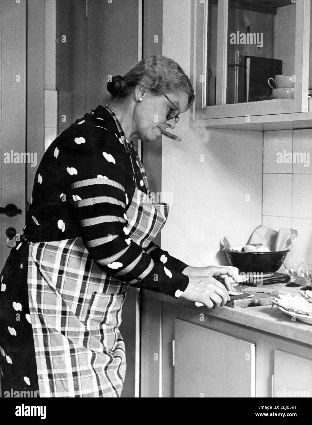 A houswife smoking a cigar in the kitchen - Denmark - c. 1950s Stock Photo